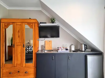a kitchen with a cabinet with a tv on the wall at Mulligans Guest Lodge in Hermanus