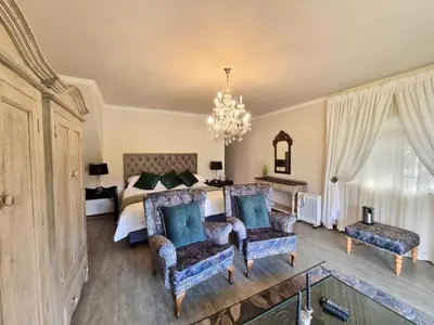 a bedroom with a bed and two chairs and a chandelier at Mulligans Guest Lodge in Hermanus