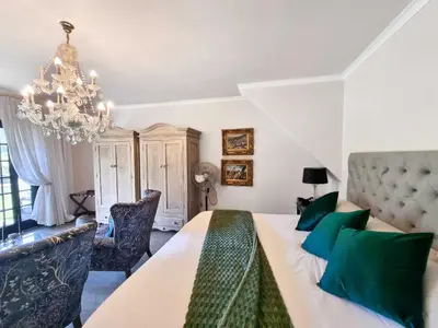 a bedroom with a large bed and a chandelier at Mulligans Guest Lodge in Hermanus