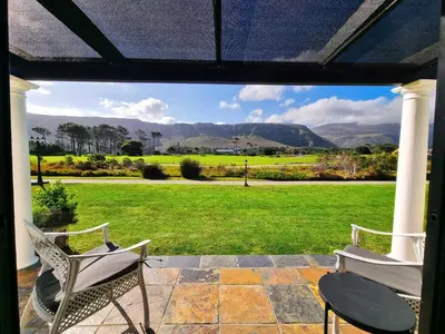 a patio with two chairs and a view of a field at Mulligans Guest Lodge in Hermanus