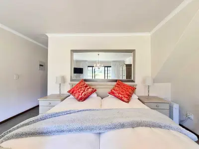 a bedroom with a large bed with red pillows at Mulligans Guest Lodge in Hermanus