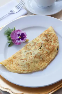 a tortilla on a white plate with a purple flower at Hermanus Boutique Guest House in Hermanus