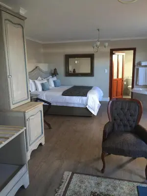 a bedroom with a bed with a mirror and a chair at Hermanus Boutique Guest House in Hermanus