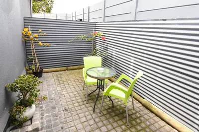 a patio with a table and chairs and a fence at OnQ Accommodation in Bellville