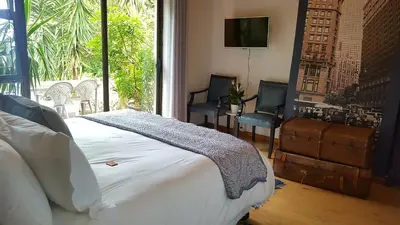 a bedroom with a bed and two chairs and a television at The Wild Fig in Durbanville