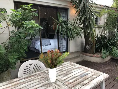 a wooden table with a vase of flowers on a patio at The Wild Fig in Durbanville