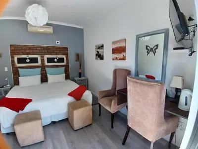 a bedroom with a bed and a desk and chairs at Ons Stee Bed and Breakfast in Wellington