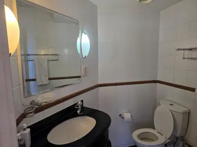 a bathroom with a sink and a toilet and a mirror at False Bay Inn in Strand