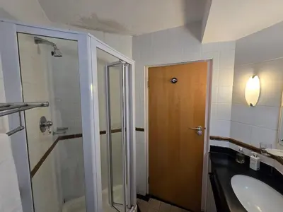 a bathroom with a shower and a sink and a toilet at False Bay Inn in Strand