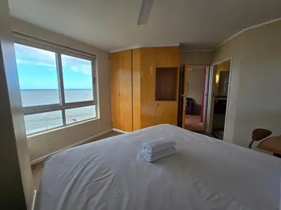 a bedroom with a bed with a view of the ocean at False Bay Inn in Strand