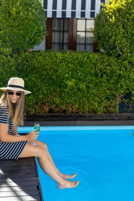 a woman in a hat sitting on a bench with a drink at Lemoenkloof Boutique Hotel in Paarl