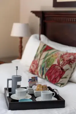 a tray with cups and plates of food on a bed at Lemoenkloof Boutique Hotel in Paarl