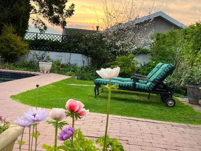 a green bench sitting in a yard with flowers at Penelope's Stellenbosch in Stellenbosch