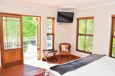a bedroom with a bed and a tv on the wall at Penelope's Stellenbosch in Stellenbosch