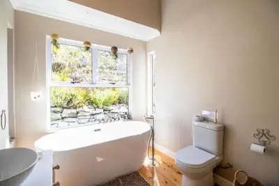 a bathroom with a white tub and a window at Tranquility Heights in Pringle Bay