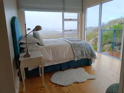 a bedroom with a bed and a large window at Tranquility Heights in Pringle Bay