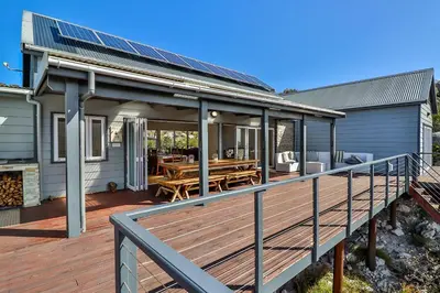 a house with a deck with solar panels on it at Tranquility Heights in Pringle Bay