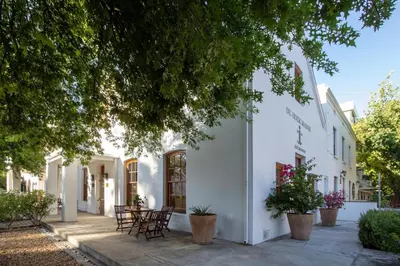 a white building with tables and chairs on a sidewalk at De Hoek Manor in Stellenbosch