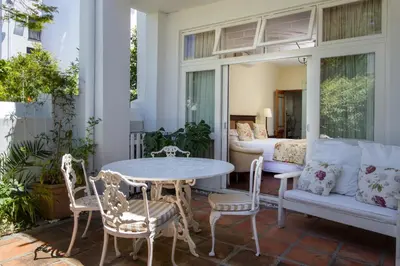 a porch with a table and chairs and a bed at De Hoek Manor in Stellenbosch