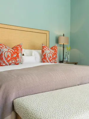 a bedroom with two beds with orange and white pillows at Le Quartier Francais in Franschhoek