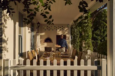 a woman standing on the porch of a house at Le Quartier Francais in Franschhoek