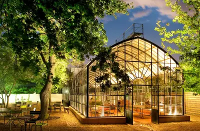 a glass greenhouse in a garden with tables and chairs at Babylonstoren in Simondium