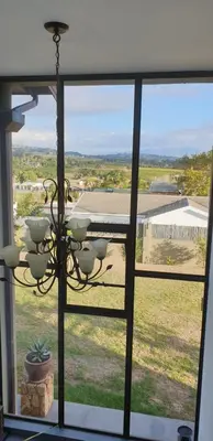 a chandelier in front of a window with a view at Modern spacious home in heart of Cape Winelands in Somerset West
