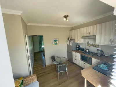 a kitchen with white cabinets and a table and chairs at Lemon Tree Cottage in Edgemead