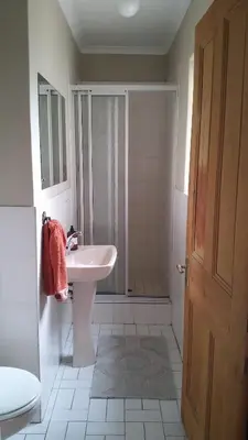a white bathroom with a sink and a shower at Getaway on Peck Way in Edgemead