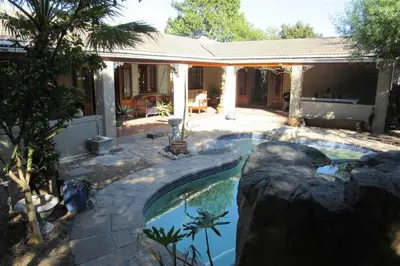 a swimming pool in a backyard with a rock wall at Getaway on Peck Way in Edgemead