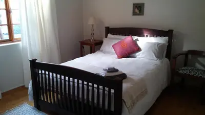 a bedroom with a bed with white sheets and pink pillows at Getaway on Peck Way in Edgemead