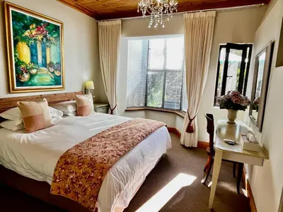 a bedroom with a large bed and a chandelier at Heuwelsig Farm Cottages in Franschhoek