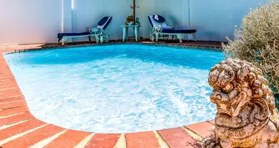a swimming pool with two chairs and a table at Bleu Cobalt Cottage in Franschhoek