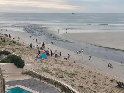 a group of people walking on the beach at Cape Beach Penthouse in Cape Town