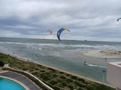 two kites flying over the ocean on a beach at Cape Beach Penthouse in Cape Town