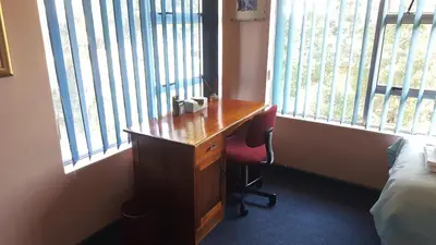 a desk with a chair in a room with windows at Durbanville Place - 3 bedroom apartment in Durbanville