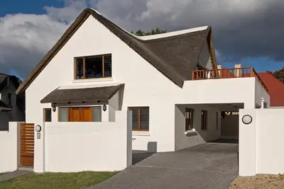a white house with a black roof at Pacem cottage in Hermanus
