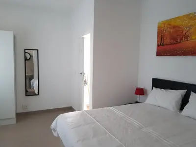 a white bedroom with a bed and a painting on the wall at Fama Lodge Rm13 in Cape Town