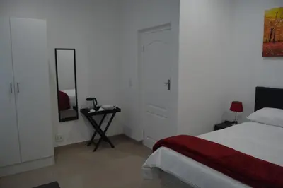 a white bedroom with a bed and a mirror at Fama Lodge Rm13 in Cape Town