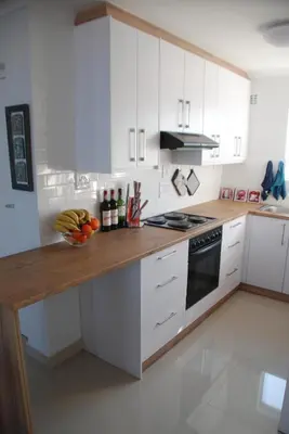 a kitchen with white cabinets and a bowl of fruit on a counter at Nothing But View in Hermanus