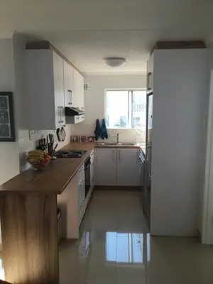 a kitchen with white cabinets and a wooden counter top at Nothing But View in Hermanus