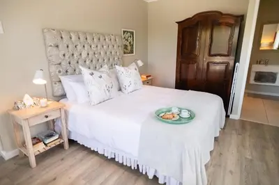 a bedroom with a white bed with a plate of food on it at Protea & Pincushion Cottages in Hermanus
