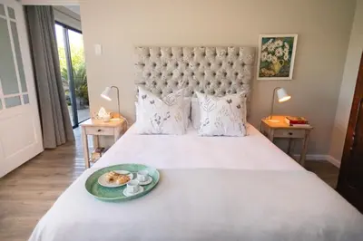 a bedroom with a large bed with a plate of food on it at Protea & Pincushion Cottages in Hermanus