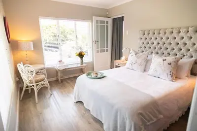 a bedroom with a large white bed and a window at Protea & Pincushion Cottages in Hermanus