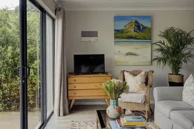 a living room with a tv on a wooden dresser at Protea & Pincushion Cottages in Hermanus