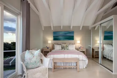 a bedroom with a bed and a large window at Protea & Pincushion Cottages in Hermanus
