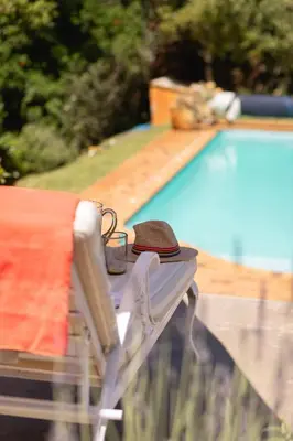 a table with a towel and a hat on it next to a pool at Protea & Pincushion Cottages in Hermanus