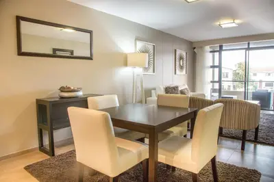 a dining room with a table and chairs at Modern 2 bedroom with underground parking 1 mins from beach-205 La Cabina, Blouberg, Cape Town in Bloubergstrand