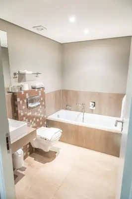 a bathroom with a tub and a toilet and a sink at Modern 2 bedroom with underground parking 1 mins from beach-205 La Cabina, Blouberg, Cape Town in Bloubergstrand