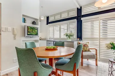 a dining room with a wooden table and green chairs at Eikehoff 25 in Stellenbosch